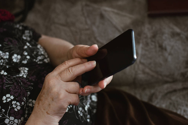 Beautiful hands of a old woman. Old woman's hands with wrinkles touching screen her smartphone - Fotó, kép