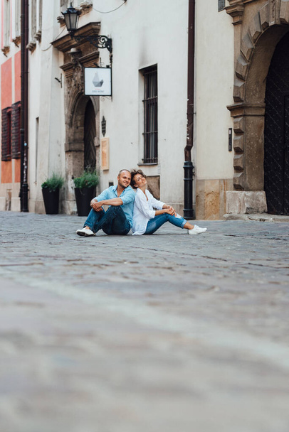Ένας άντρας και ένα κορίτσι περπατούν ευτυχισμένα το πρωί στους άδειους δρόμους της παλιάς Ευρώπης. - Φωτογραφία, εικόνα