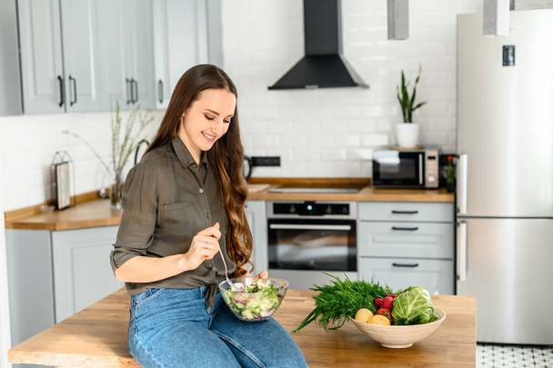 Woman eating healthy food in cozy kitchen - Foto, Bild