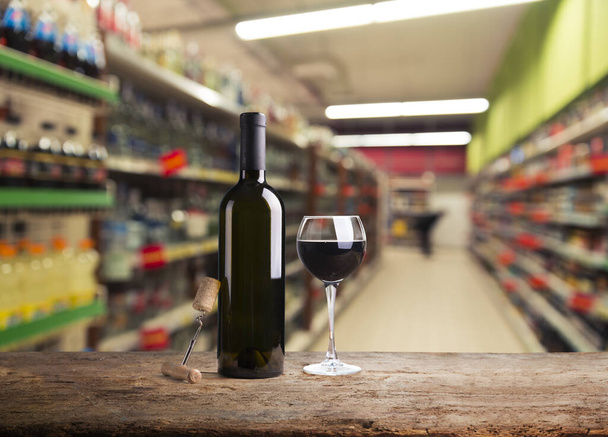 Mesa de madera y vino Botella de licor sobre fondo borroso estante
 - Foto, imagen