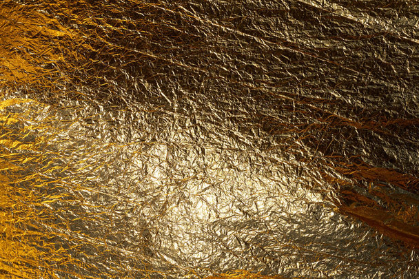 Texture of a thin crumpled sheet of foil. Crumpled foil background. Stock photo foil. Gold chrome color. - Foto, afbeelding
