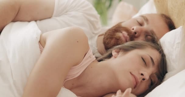 Portrait of young loving family cuddling in bed while sleeping in early morning. Handsome bearded man hugging woman while lying on bed and dreaming. Concept of relationship. - Footage, Video