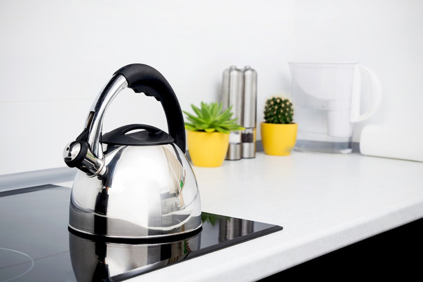 Steel kettle in modern kitchen with induction stove - Fotoğraf, Görsel