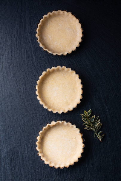 Концепция продуктов Домашний эмти пирог корка для органического лимона, лаймовые пироги или мини-пирог на черной доске из камня
 - Фото, изображение
