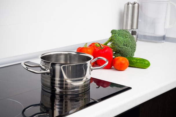 Pot and vegetables in modern kitchen with induction stove - Foto, immagini
