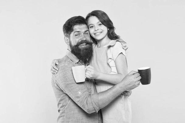 Good morning. Having coffee together. Lovely family tradition. Drinking tea. Bearded man and happy girl holding mugs. Father and daughter hot drink. Drink water. Drink fresh juice. Breakfast concept - Foto, afbeelding