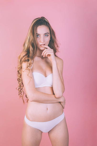 joven delgado sexy chica en ropa deportiva blanca posando sobre un fondo rosa
 - Foto, imagen