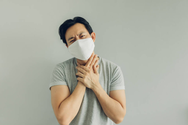 Sick man wearing white hygienic mask in grey t-shirt in concept of virus. - Foto, imagen