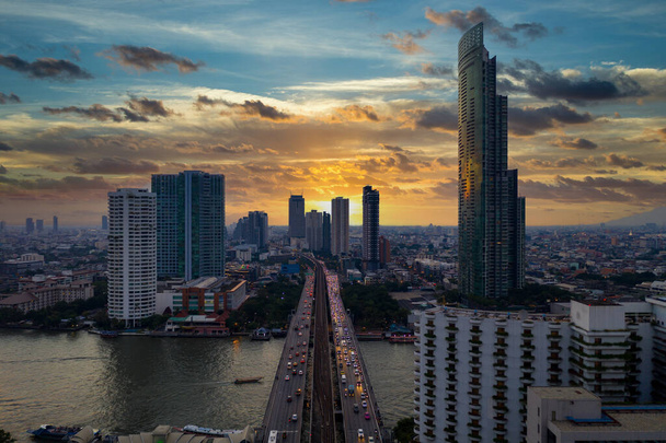 Luftaufnahme Skyline und Wolkenkratzer der Stadt Bangkok an der Sathorn Road Geschäfts- und Finanzviertel in der Innenstadt von Bangkok, Panorama der Taksin-Brücke über den Fluss Chao Phraya, Bangkok, Thailand bei Sonnenuntergang. - Foto, Bild