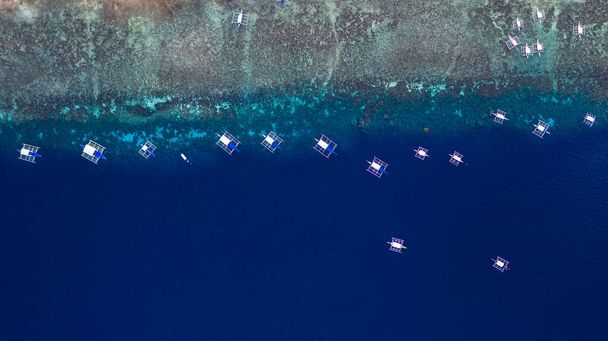 Vista aérea de arriba hacia abajo del barco que se mueve en mar abierto con agua clara y turquesa sobre el arrecife de coral, barco salió de la laguna tropical, Moalboal, Oslob, Isla Cebú, Filipinas
. - Foto, imagen