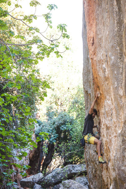 Een sterke man overwint een moeilijke klimroute op een natuurlijk terrein. Rotsklimmer traint op de Turkse rotsen. Actieve levensstijl. Extreme hobby. - Foto, afbeelding