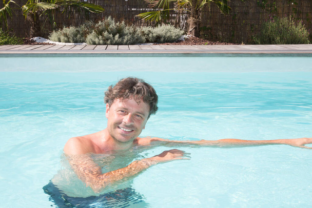 Šťastný pohledný muž v bazénu v prázdninovém konceptu - Fotografie, Obrázek
