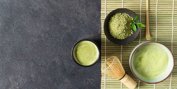 Green matcha tea drink and tea accessories on black background top view. Japanese tea ceremony concept. Chashaku spoon and chasen bamboo whisk for brewing matcha tea. - Foto, afbeelding