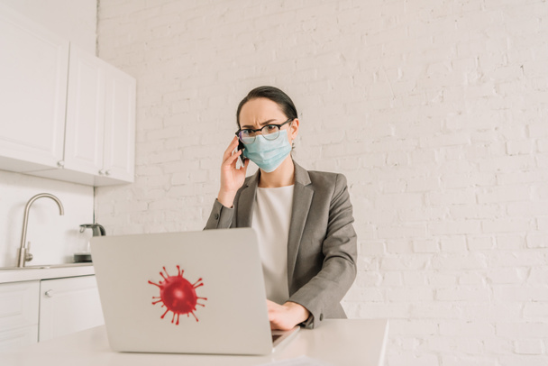 komoly üzletasszony orvosi maszk és szemüveg beszél okostelefon közelében laptop koronavírus baktérium matrica - Fotó, kép