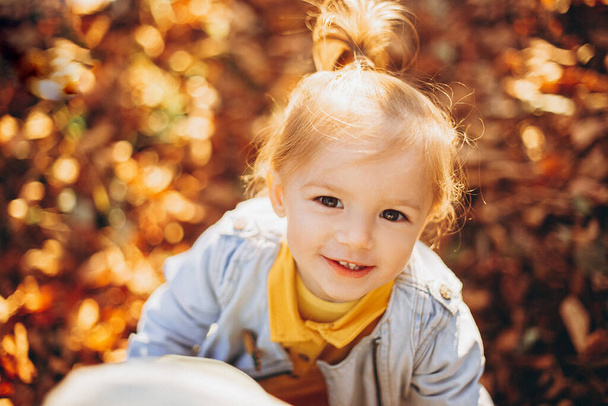 piccola bella ragazza in posa per una foto mentre cammina con i suoi genitori nel parco autunnale, un bambino infinitamente felice e gioioso, messa a fuoco selettiva, effetto rumore - Foto, immagini