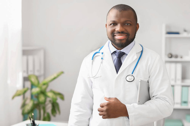 Мужчина афро-американский врач с планшетным компьютером в клинике
 - Фото, изображение