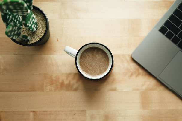 Workspace with laptop and coffee cup on wooden desk. - 写真・画像
