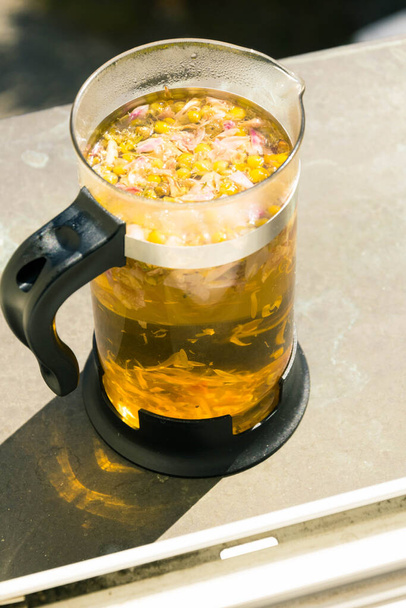 Hot medicine herbal chamomile flowers yellow tea in french press tea pot  - Photo, Image