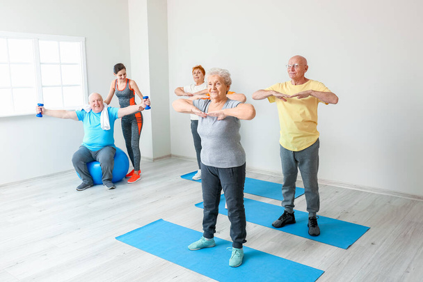 Elderly people exercising in gym - Фото, изображение