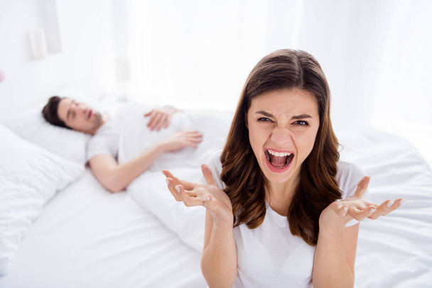 Photo of two people furious outrage girl cant sleep her husband snore loud make awake she scream angry shout wear white t-shirt in house indoors - Photo, Image