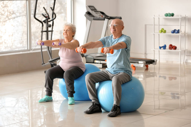 Elderly man and woman exercising in gym - Photo, Image