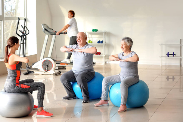 Junge Trainerin trainiert mit Senioren beim Training im Fitnessstudio - Foto, Bild