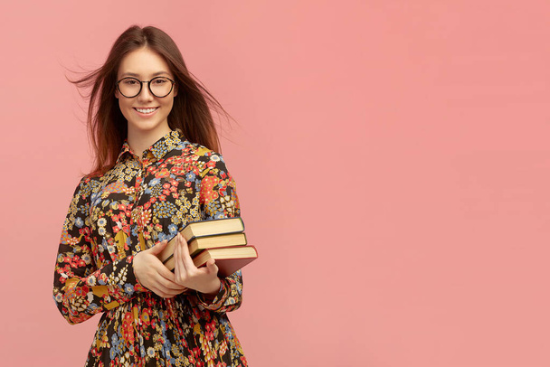 A young pretty girl student, with books from the library, smiling sweetly. Distance learning of foreign languages. - Foto, Imagen
