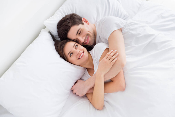 High angle above view photo cute lady husband guy couple lying comfortable sheets bed white blanket morning hugging joyful hold hands look eyes wear pajama room indoors - Fotó, kép
