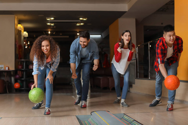 Friends playing bowling in club - Фото, изображение
