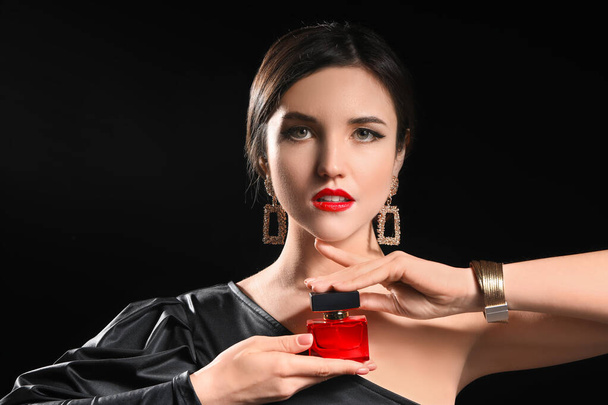 Krásná mladá žena s parfémem na tmavém pozadí - Fotografie, Obrázek