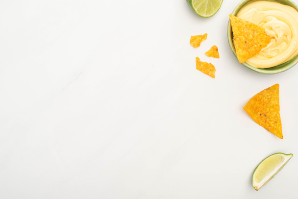 top view of corn nachos with lime and cheese sauce on white background - Foto, afbeelding