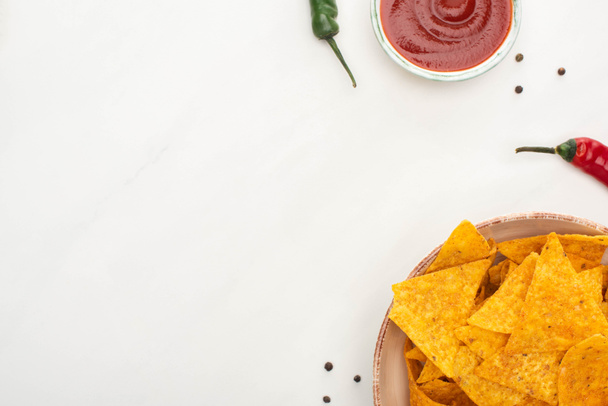 top view of corn nachos with chili peppers, ketchup on white background - 写真・画像