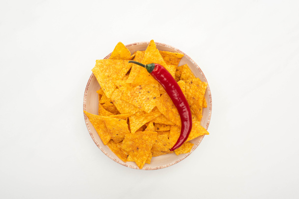 vrchní pohled na kukuřičné nachos s červeným chilli paprikou na bílém pozadí - Fotografie, Obrázek