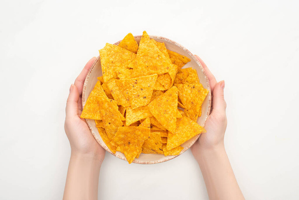 cropped view of woman holding bowl of corn nachos with on white background - Photo, Image