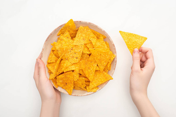 cropped view of woman holding bowl of corn nachos with on white background - Foto, afbeelding