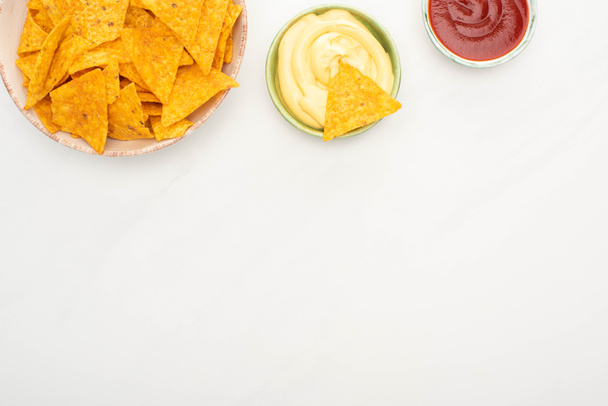 top view of corn nachos with ketchup and cheese sauce on white background - Fotografie, Obrázek