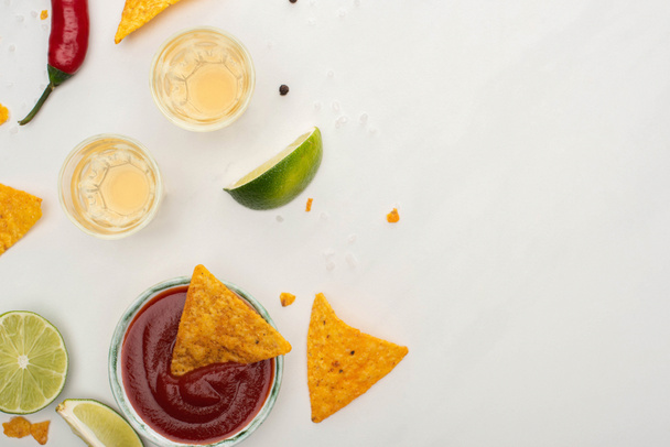 top view of corn nachos with lime, chili, ketchup and tequila on white background - Foto, Bild