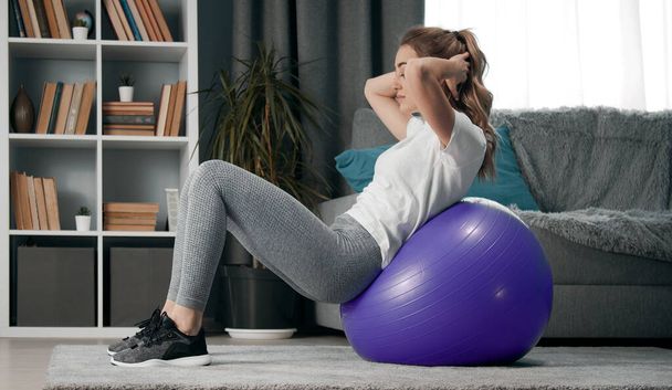 Woman leaning backwards on fitball - 写真・画像
