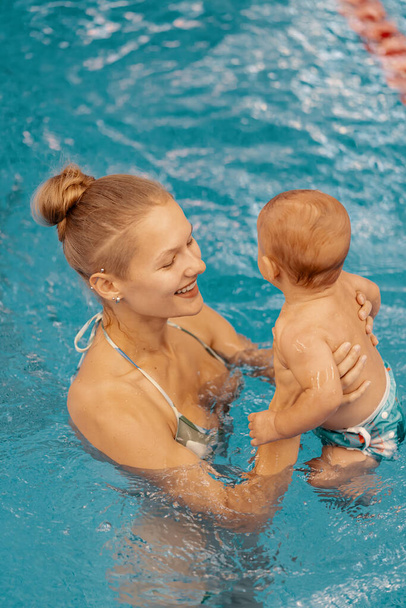Mother and little son having fun in a swimming pool - Photo, Image