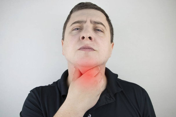 Человек прикасается к больному горлу и шее, поворачивается от раздражения и воспаления. Боль в горле при глотании, подозрении на фарингит или кислотный рефлюкс
. - Фото, изображение