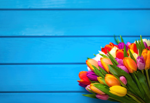Colorful bouquet of tulips on blue wooden background. Spring flowers. Greeting card with copy space for Valentine's Day, Woman's Day and Mother's Day. Top view. - Photo, Image