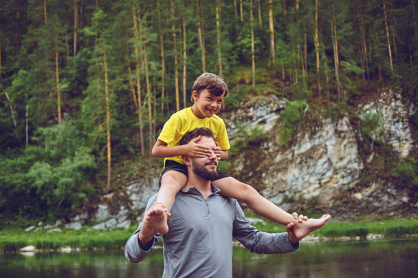Отец и сын улыбаются, проводя время вместе. Мальчик сидит на шее отца
 - Фото, изображение