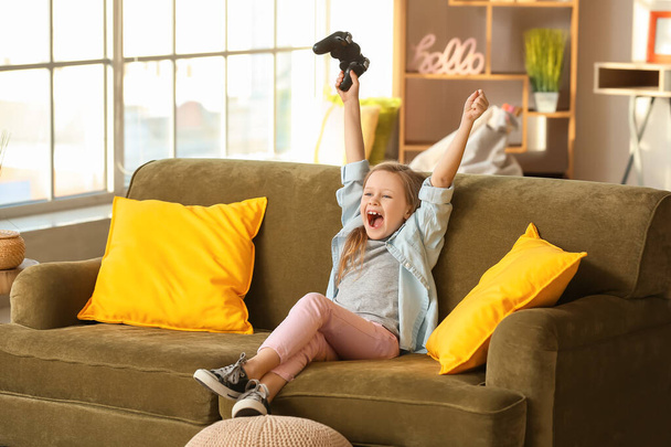 Happy little girl playing video games at home - Zdjęcie, obraz