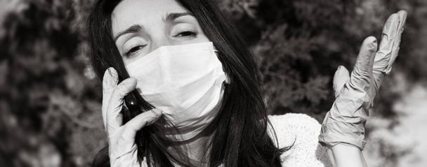 Giovane donna in maschera medica con un telefono cellulare comunica emotivamente e gesti
 - Foto, immagini