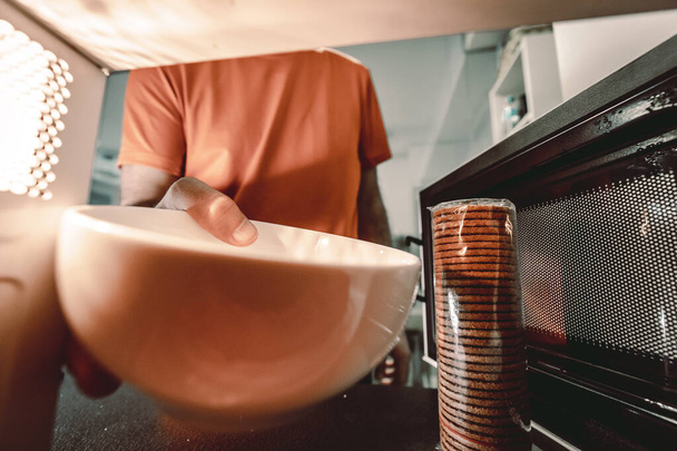 A young man heating the milk in the microwave for breakfast - Photo, image