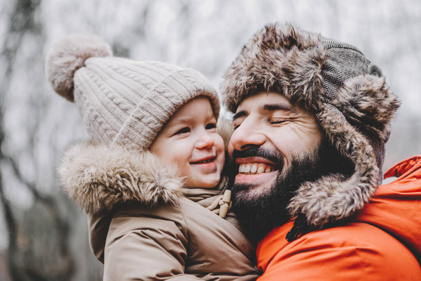 Handsome young dad and his little sweet daughter have fun outdoors in winter. Happy family spending time together. Family concept. - Foto, imagen