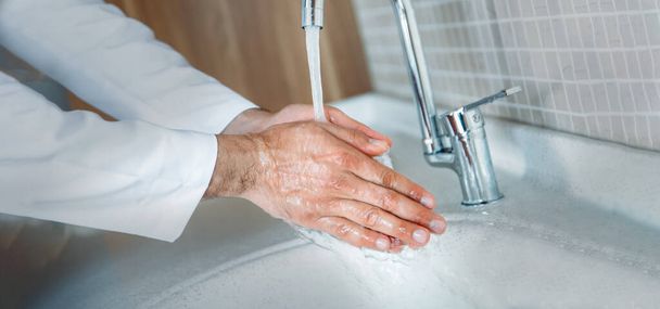 L'uomo si lava le mani correttamente con sapone per essere protetto per l'infezione da pandemia di Coronavirus 2019-nCoV. Il medico mostra come lavarsi correttamente le mani
. - Foto, immagini