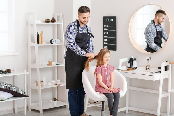 Hairdresser working with little girl in salon - Foto, afbeelding