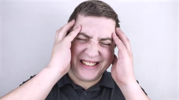 Een man houdt zijn hoofd vast met zijn handen. Gevoel van hoofdpijn, migraine en duizeligheid. Hoofdpijn door stress of overwerk - Video
