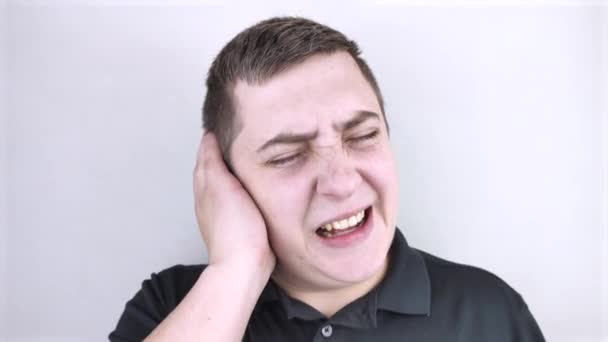 Een man houdt zijn oor vast. Oorpijn en gehoorproblemen. De mannen gezicht toont kwelling veroorzaakt door otitis media. - Video